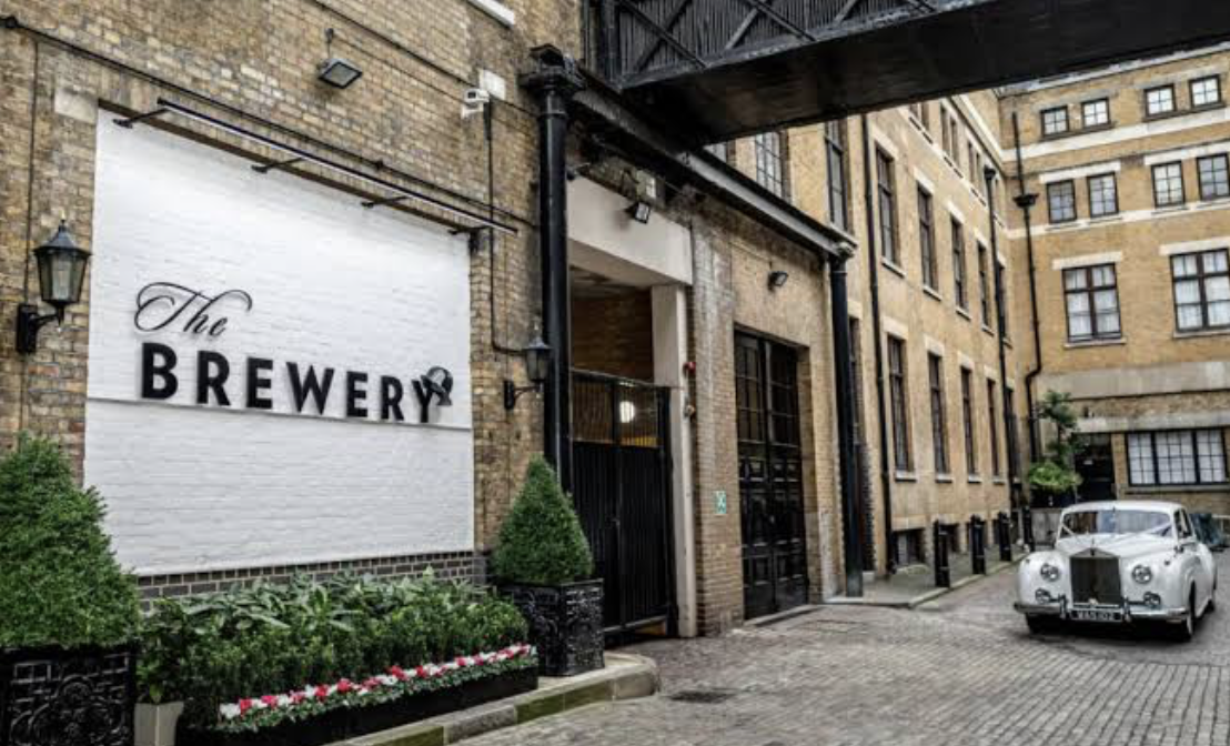 Cobbled entrance to The Brewery, London, with heritage architecture and a vintage car