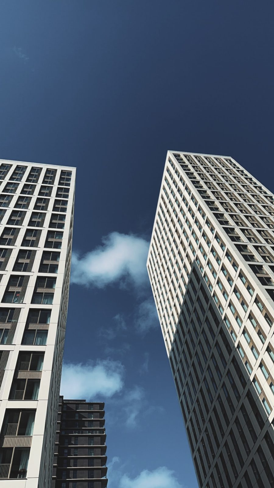Two Build-to-Rent residential towers viewed from below against a blue sky