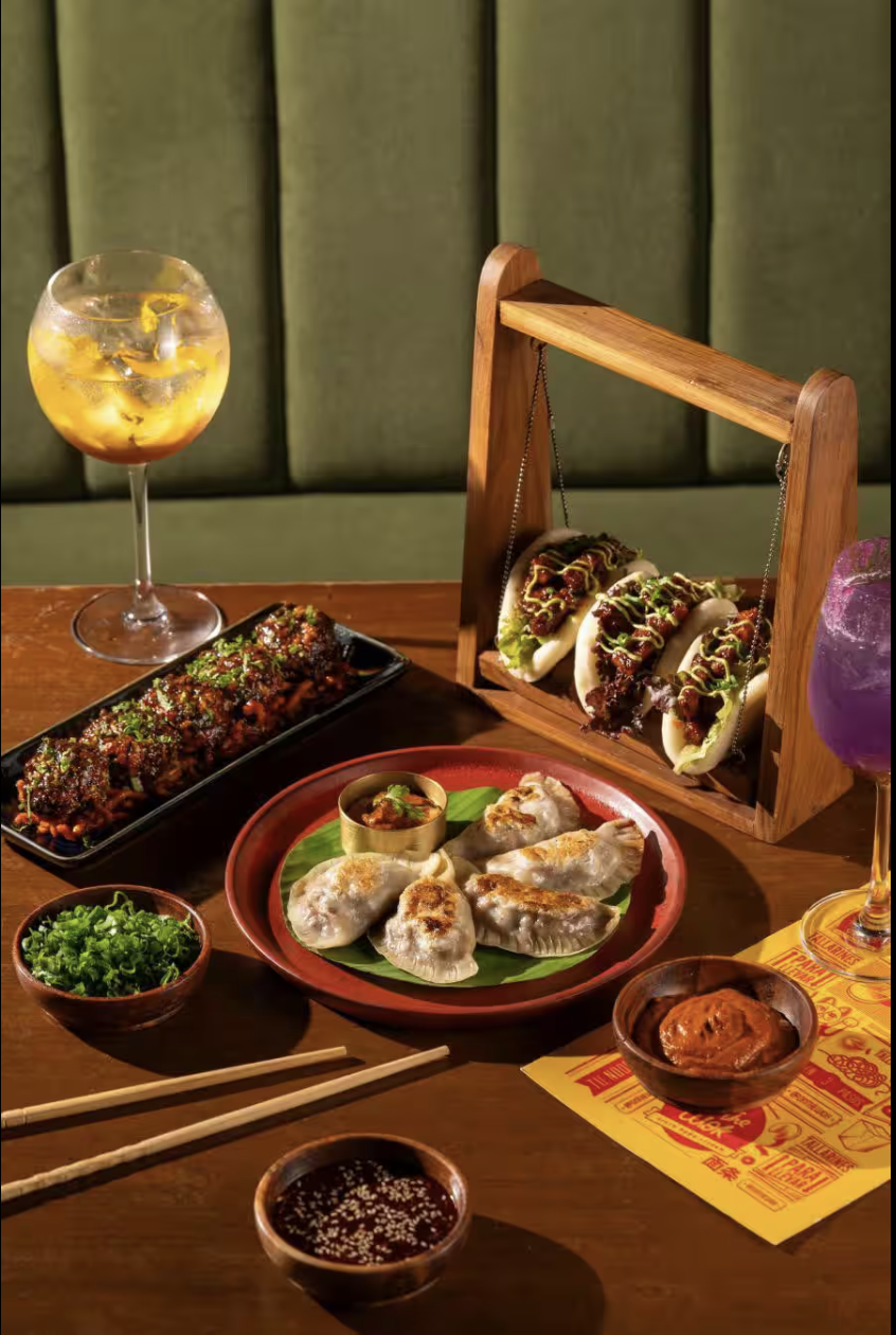 Signature Hitchki dishes and cocktails plated on a dark wooden table